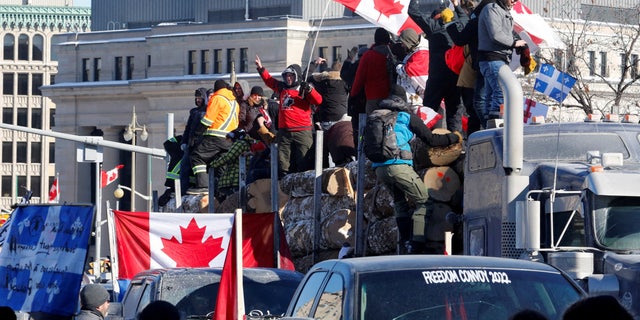 FILE FOTO: I manifestanti stanno su un rimorchio che trasporta tronchi mentre conducenti di camion e sostenitori partecipano a un convoglio per protestare contro i mandati per un vaccino contro il coronavirus (COVID-19) per i conducenti di camion transfrontalieri a Ottawa, Ontario, Canada, 29 gennaio 2022. REUTERS/PATRICK DOYLE/FILE Immagine