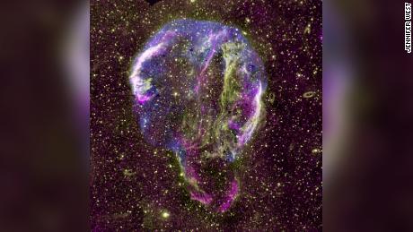 Viene mostrata un'immagine radio (viola), UV (giallo) e raggi X (blu) del residuo di supernova dell'anello Cygnus nella Via Lattea. 